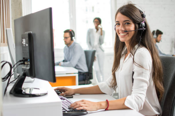 Friendly customer support service operator with headset working in call centre.